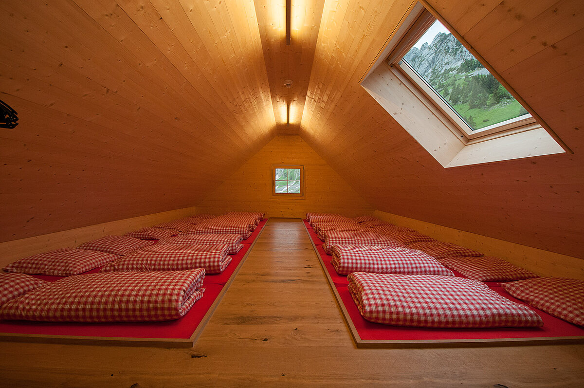 Matratzenlager mit 12 Betten und Dachfenster mit Sicht auf Felswand