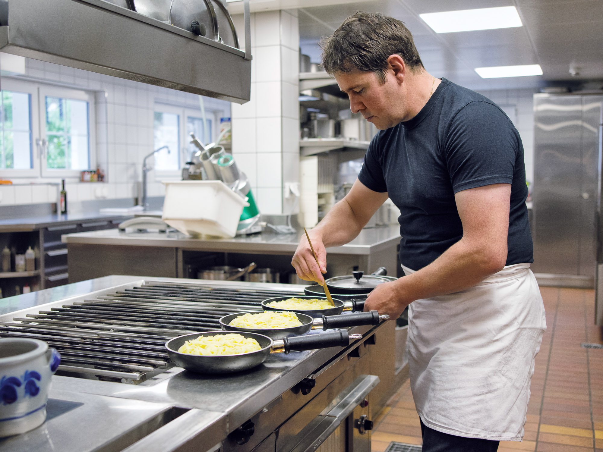 Koch kocht Rösti in Gastroküche