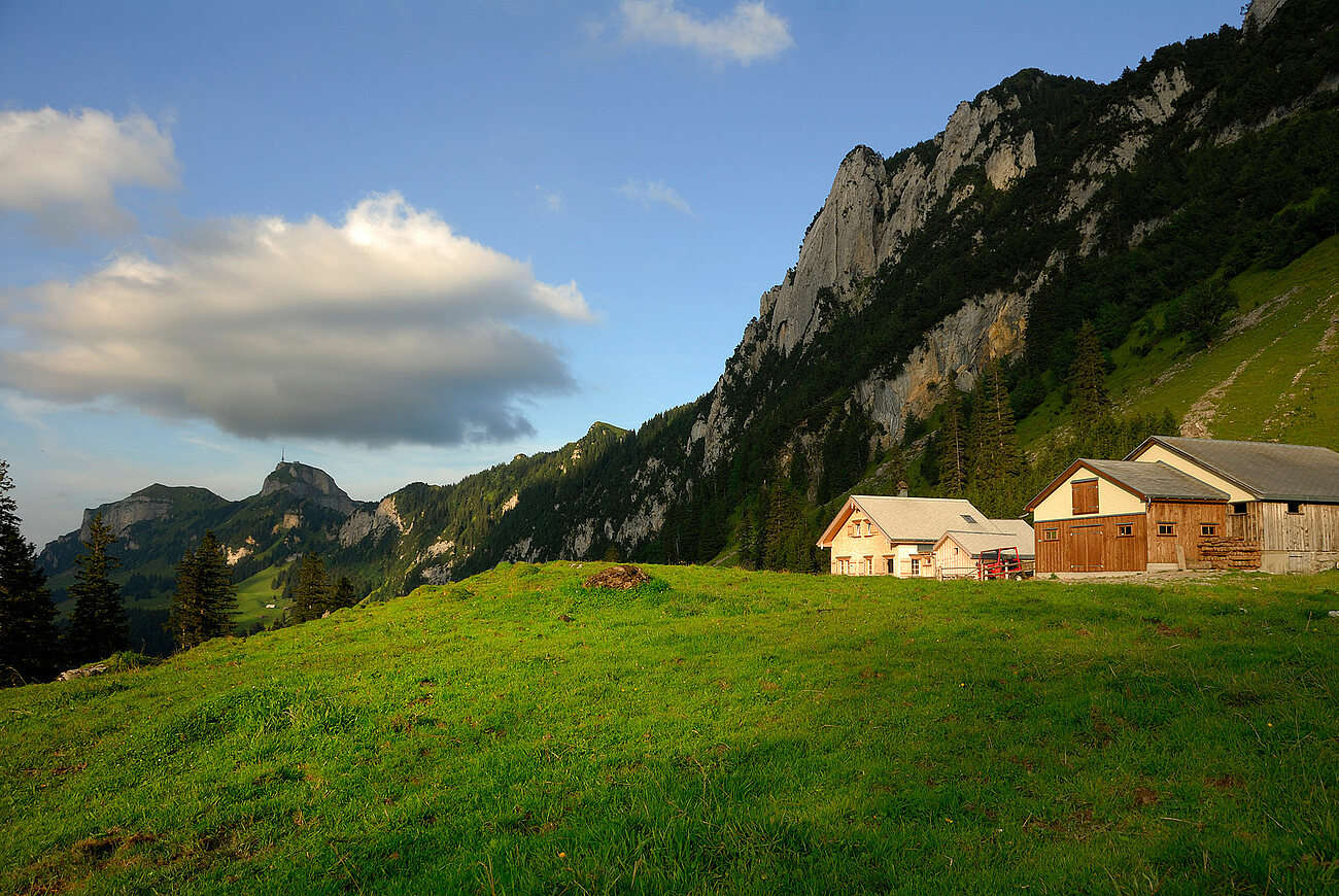 kleine Hütten stehen vor Bergkulisse und werden vom letzten Sonnenstrahl angeschienen